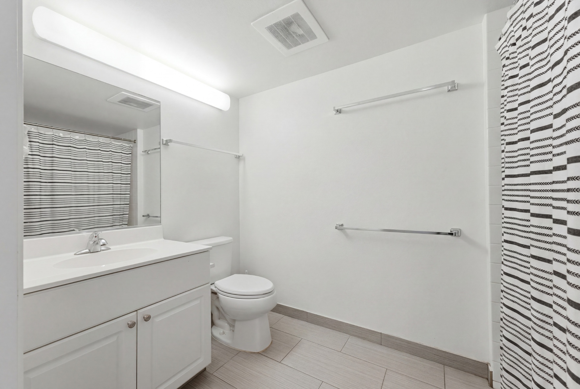 Bathroom with white vanity, toilet, and striped shower curtain