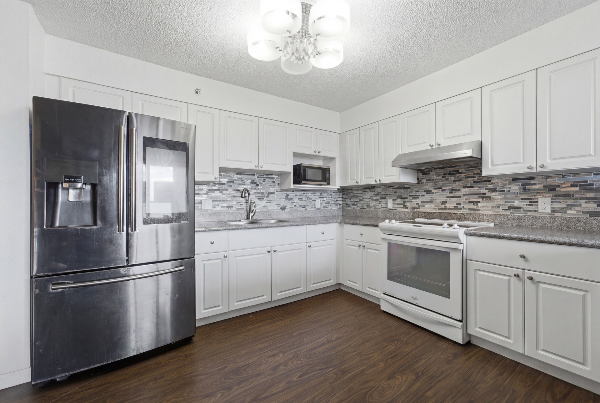 Kitchen with white cabinetry, stainless refrigerator, and tile backsplash